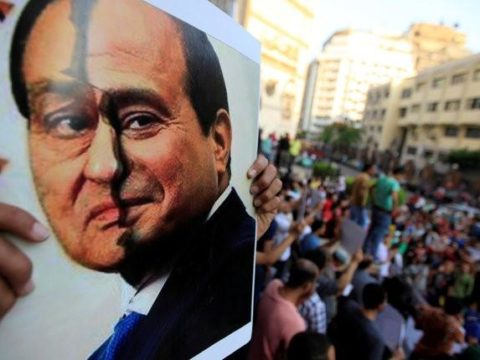 FILE PHOTO: A poster show a placard with the faces of Hosni Mubarak and Abdel Fattah al-Sisi is seen by activists during a protest in downtown Cairo